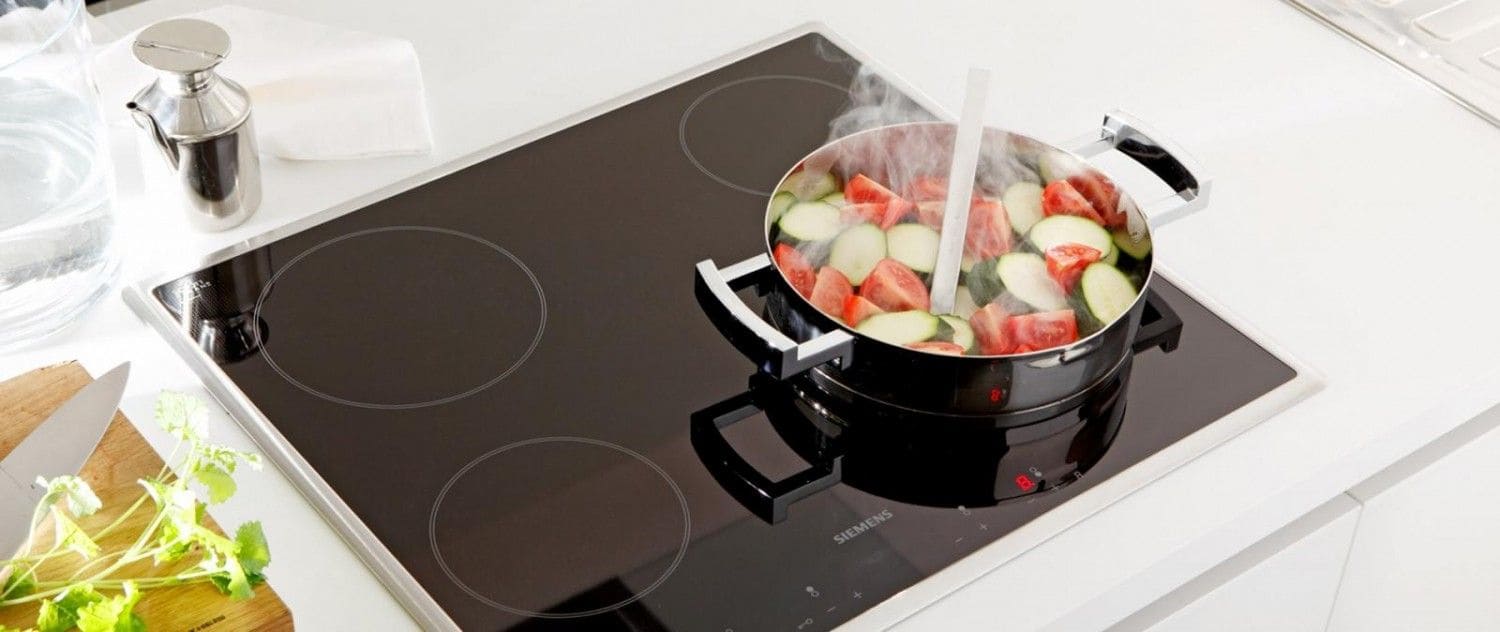 Kochfeld, auf welchem ein Topf mit Zucchini mit Paprika drin steht