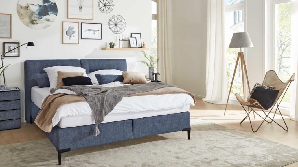 blaues Bett in eingerichtetem Schlafzimmer