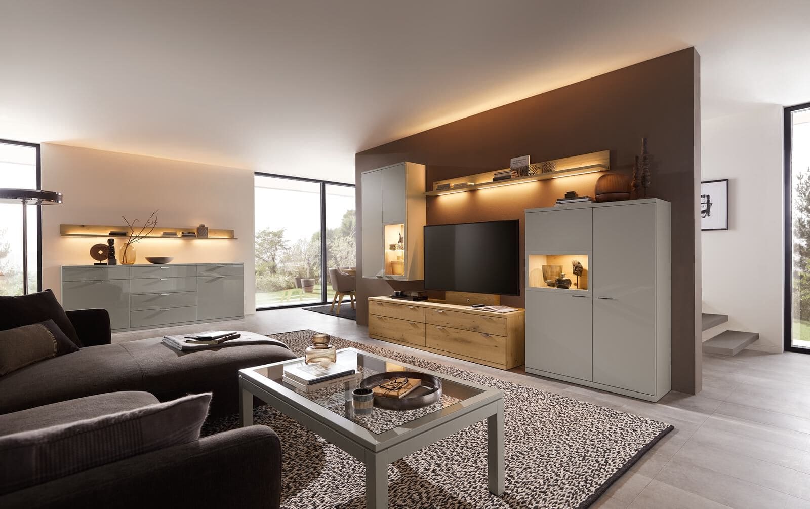 Modernes, weiss, braunes Wohnzimmer, mit braunem Sofa und integrierten Beleuchtungen in der Wohnwand