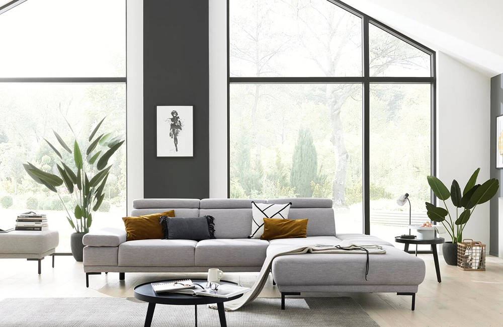 Hellgraue Couch vor einer großen Fensterfront