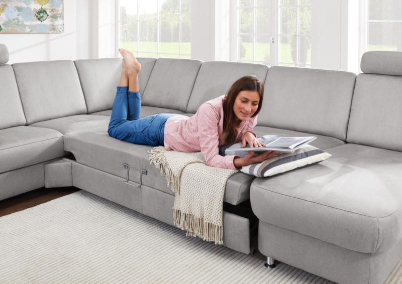 Frau, die auf einem grauen Sofa liegt