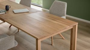 Auszugtisch von Interliving aus hellem Holz, daran stehen helle Stühle
