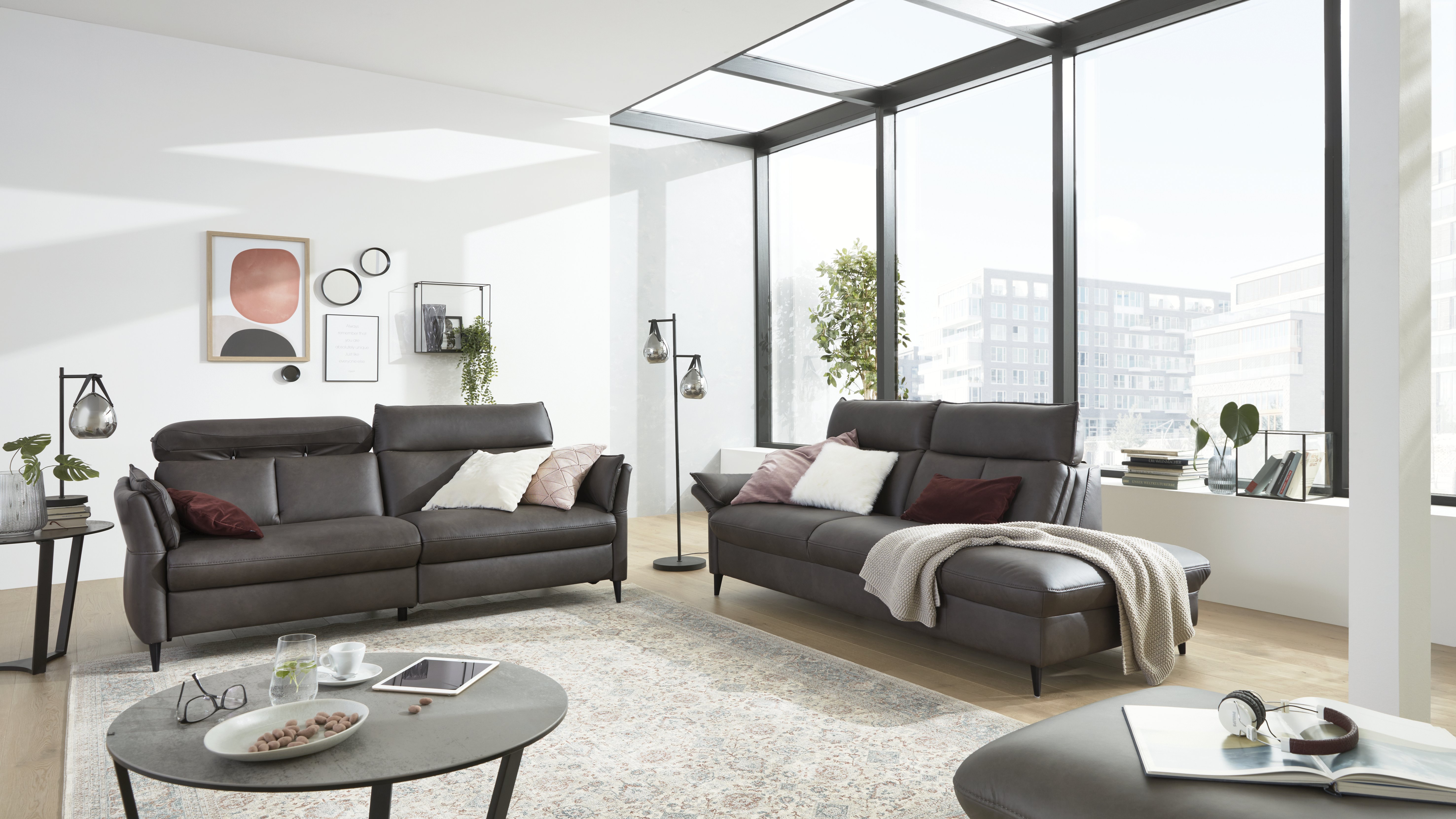 Wohnzimmer mit großen Fenstern und 2 dunklen Sofas 