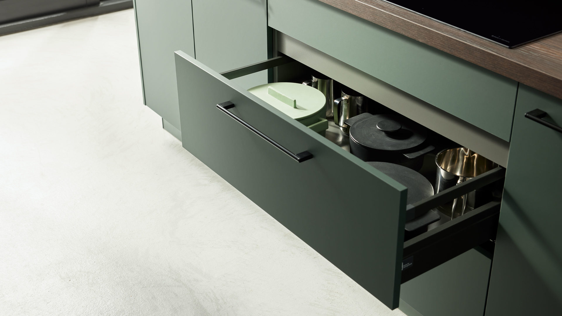 dunkelgrüne Küche mit dunkel brauner Ablage und offener Schublade