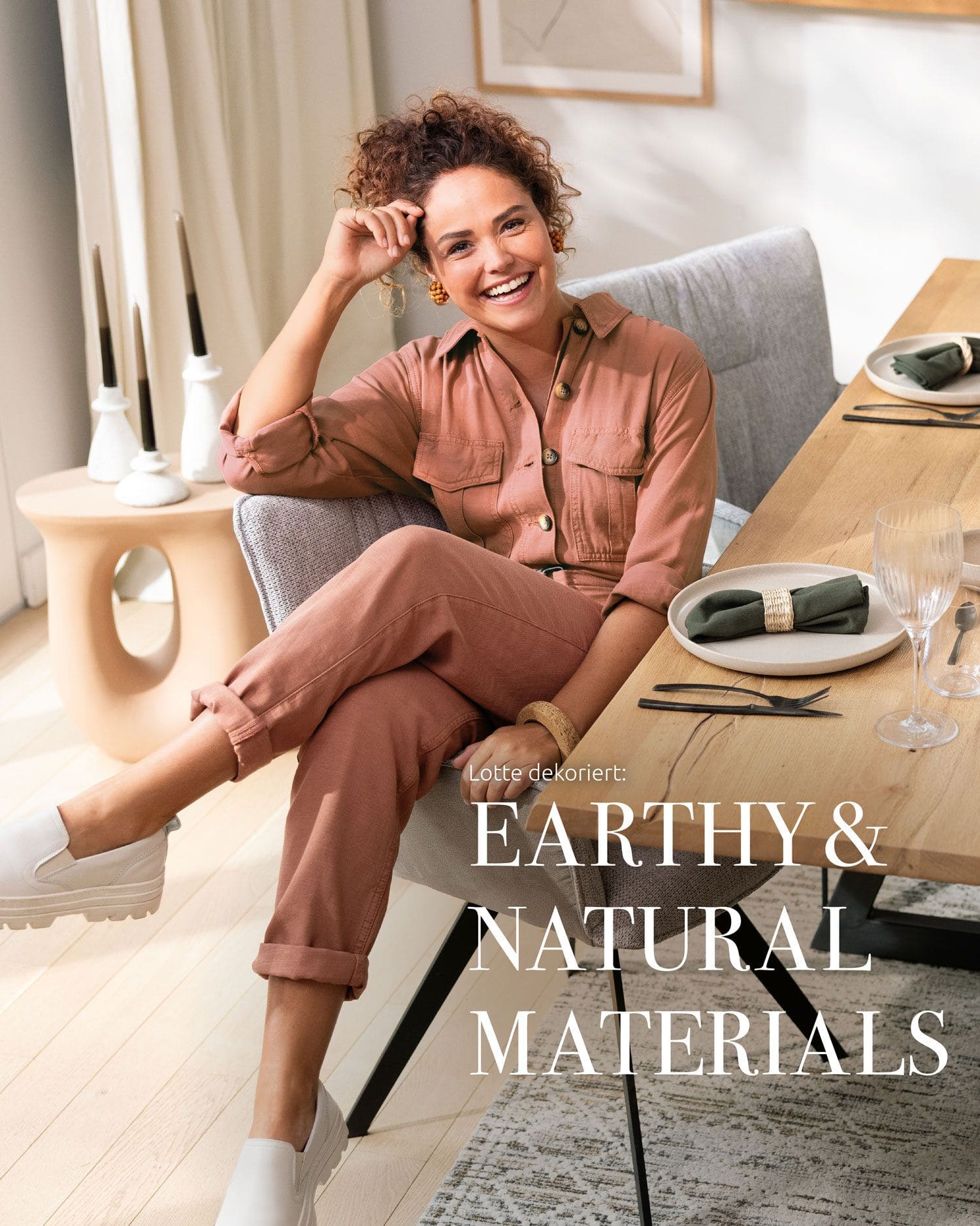 Frau, die am Tisch sitzt und lacht, auf dem Bild ist die Beschriftung ,,EARTHY & NATURAL MATERIALS''