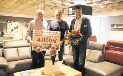 3 Männer in einem Möbelhaus, zwei von ihnen halten einen 4000€ Gutschein in die Kamera