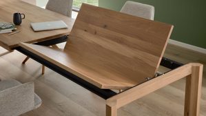 Auszugtisch von Interliving aus hellem Holz, der gerade ausgezogen wurde und die Tischplatte ausgeklappt wird