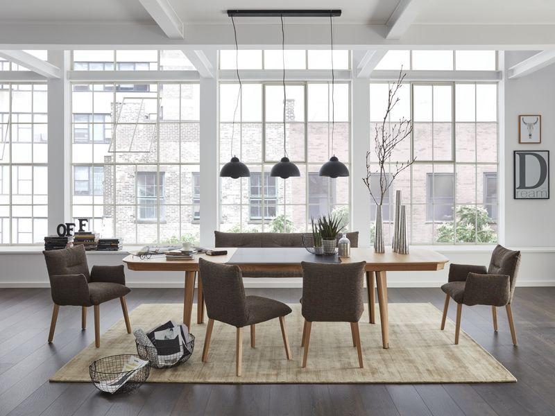 Großes Esszimmer in einem Loft mit einem modernen Tisch aus Holz und Stoffstühlen