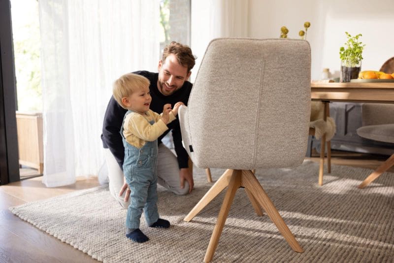 Kleines Kind, was mit seinem Vater an einem Esstisch steht und lacht