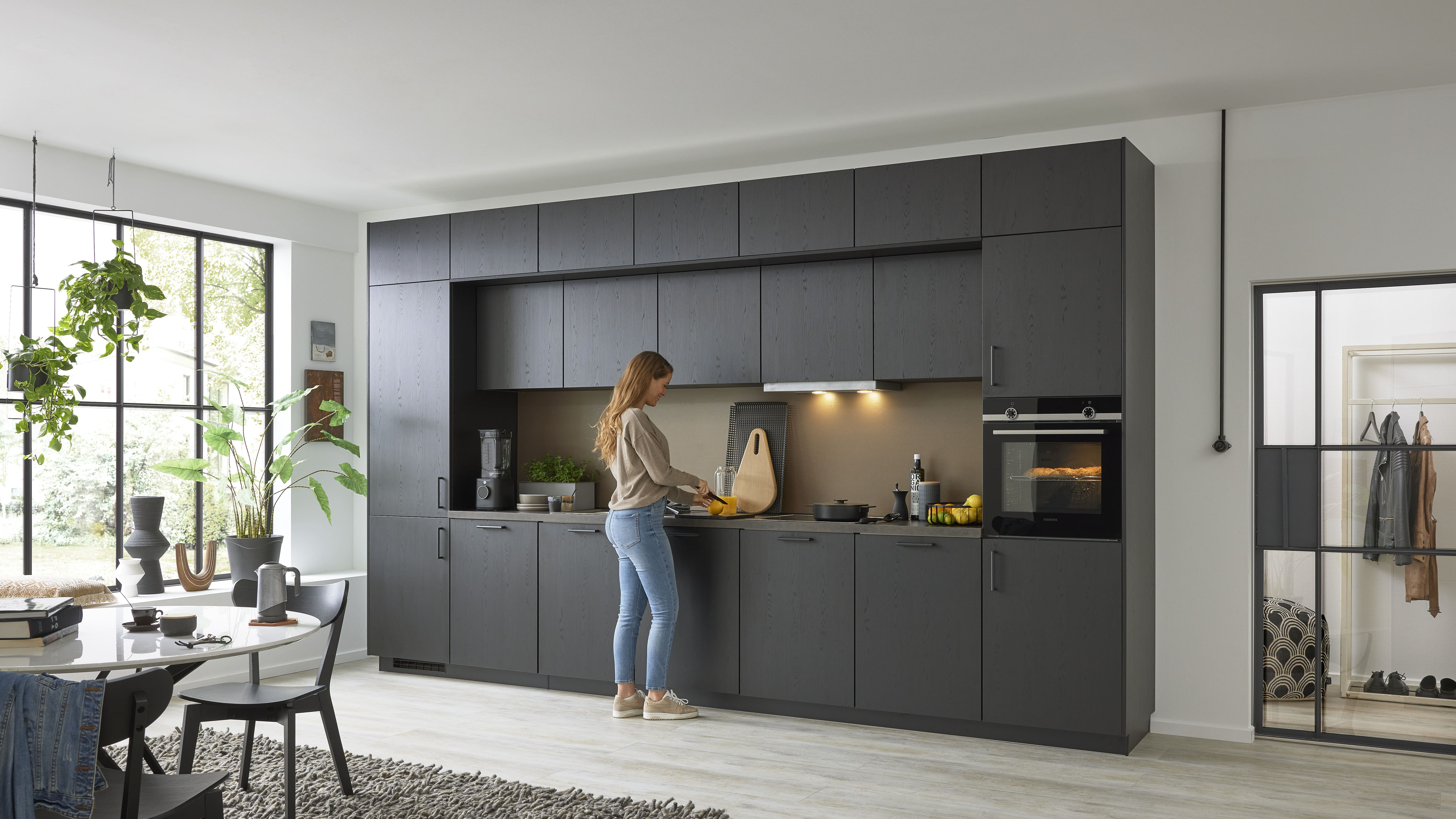 Moderne schwarze Küche, eine Frau bereitet dort Essen zu