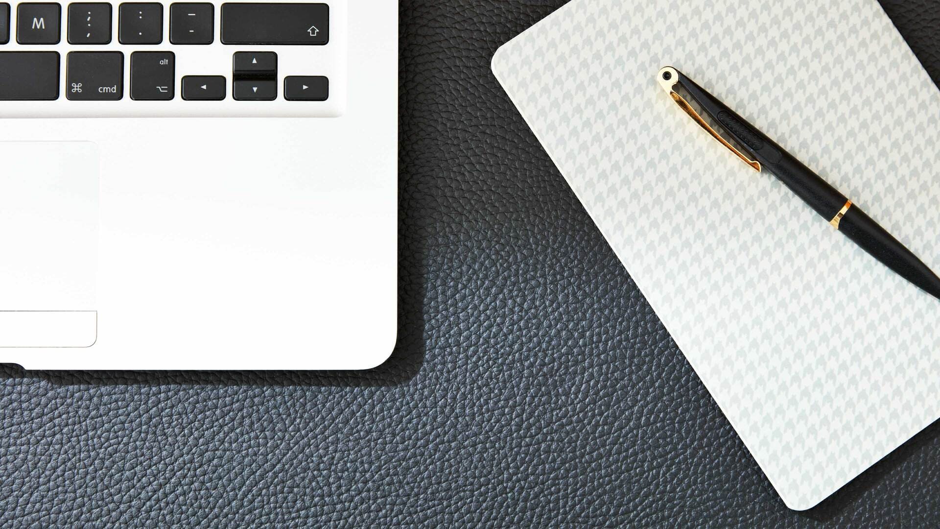 Teil einer Tastatur, daneben sieht man einen Block mit einem Kugelschreiber darauf