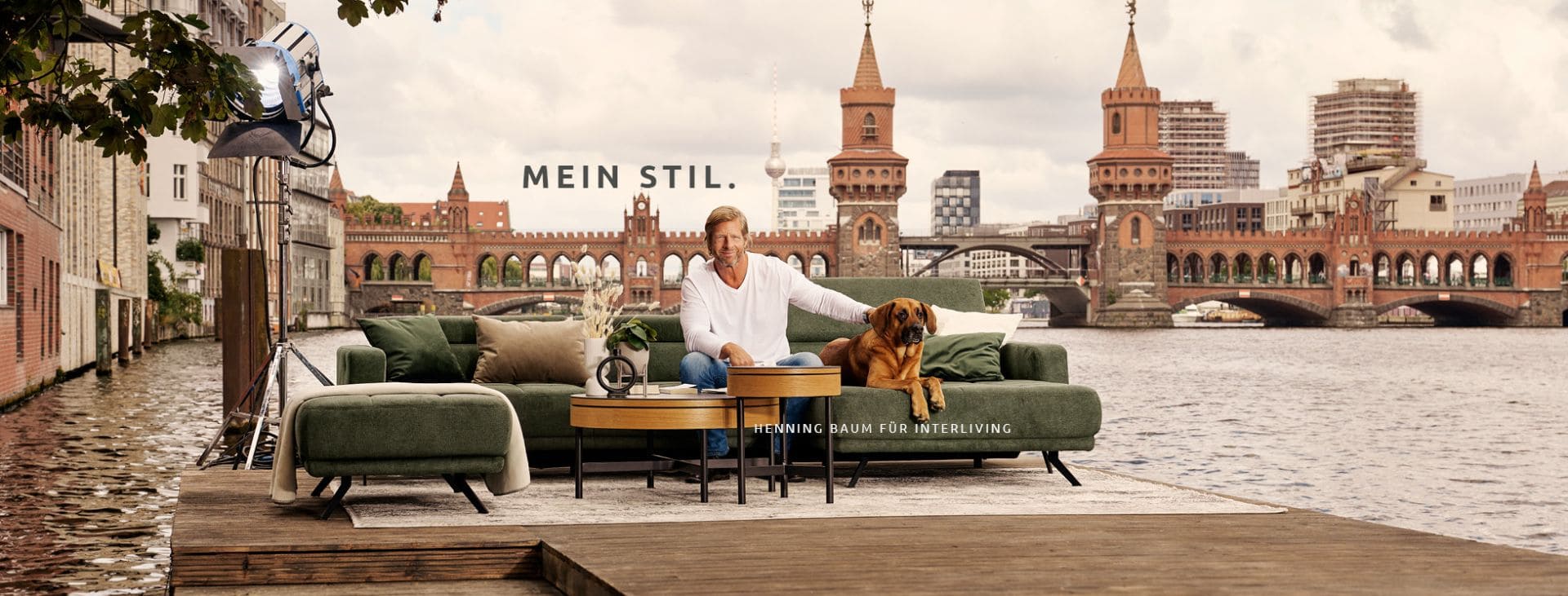 Interliving Kampagne ,it Henning Baum und einem Hund auf einem grünen Sofa