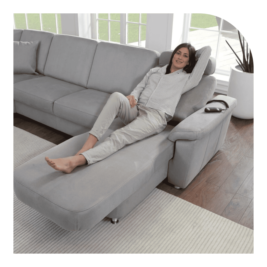 Graues Sofa, auf welchem eine Frau in gemütlicher Kleidung liegt