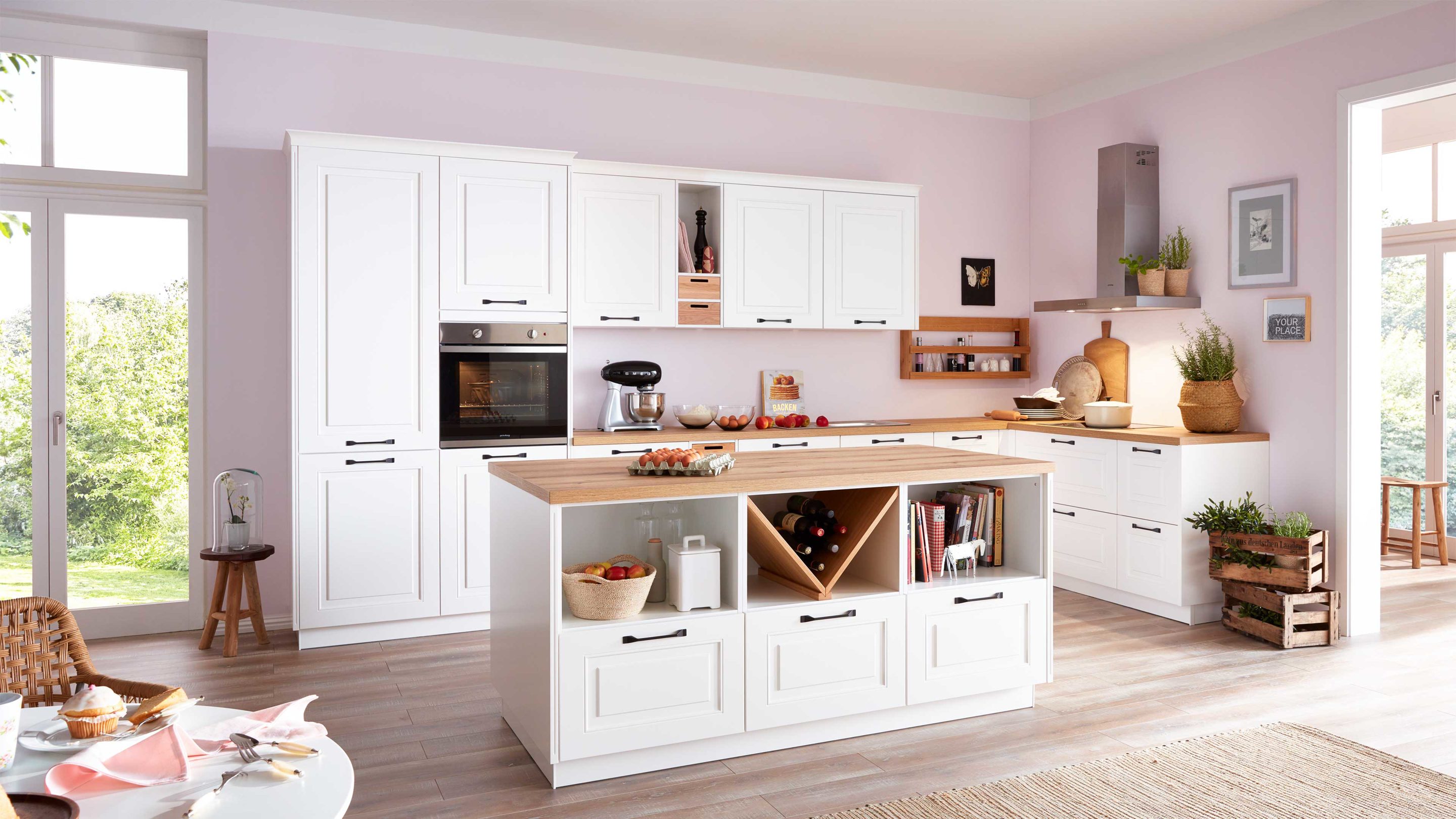 Weiße Küche im Landhausstil vor einer pastellrosanen Wand