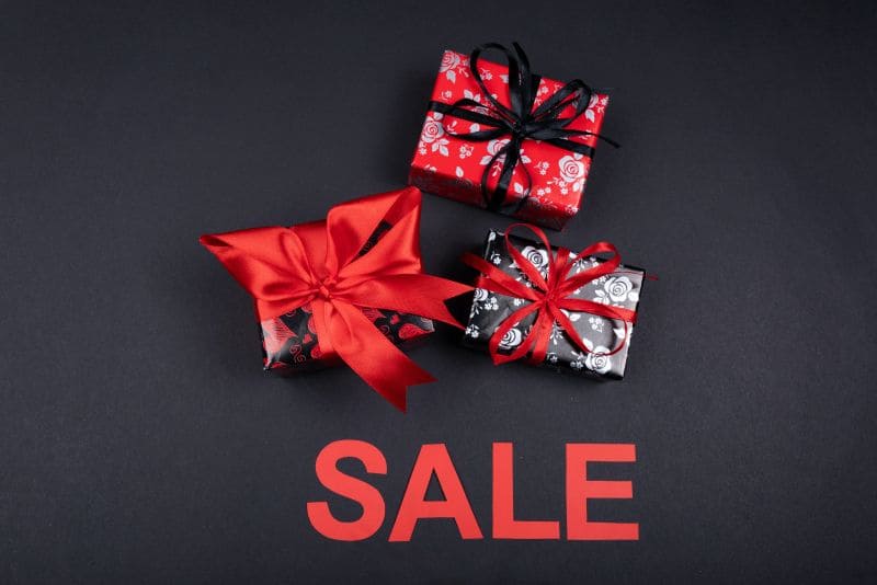 Drei kleine Geschenke und ein Schriftzug mit ,,Sale'' auf einem schwarzem Untergrund