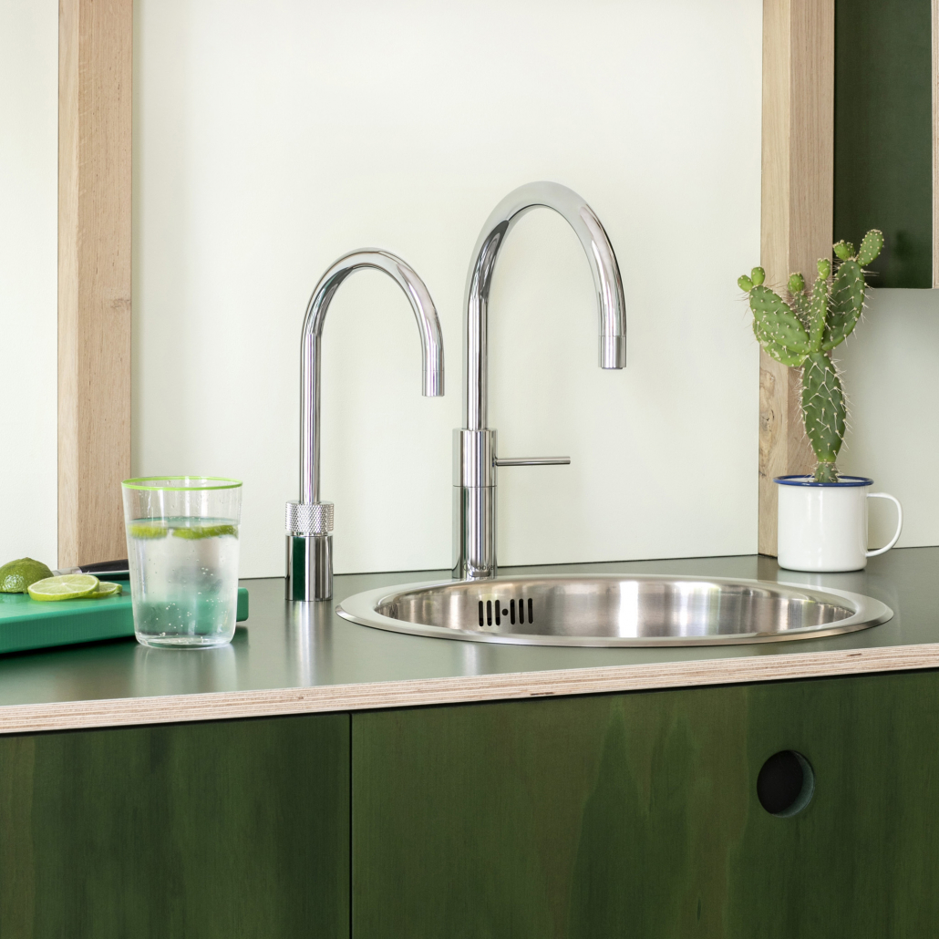 Quooker in Silber an einer silbernen Spüle einer grünen Küche